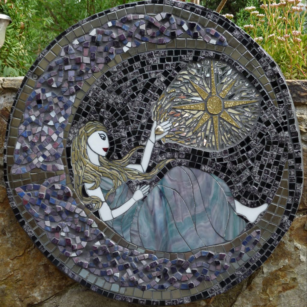 A round glass and ceramic mosaic featuring the side profile of a female figure sitting inside a crescent moon holding a heart up to a gold star.