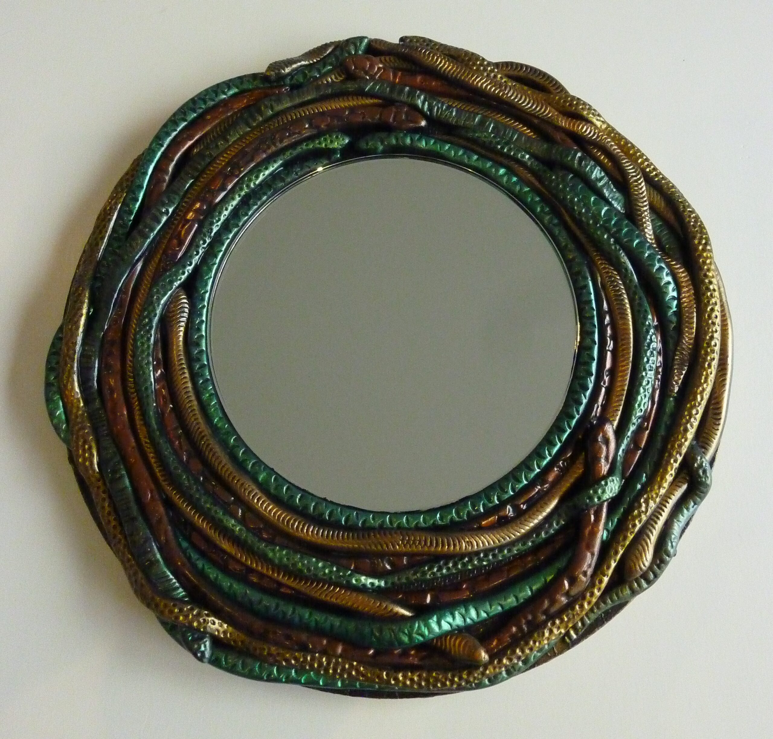 Image of a round mirror with an edging of wound snakes made from polymer clay