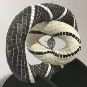 Image of a mosaic sculpture in black and white ceramic tile with copper wire and a glass bead centre. The sculpture has two main parts at perpendicular angles to each other.