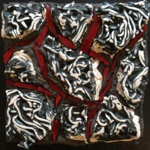 Image of a piece of broken textured ceramic with red glass pieces filling the gaps in between.