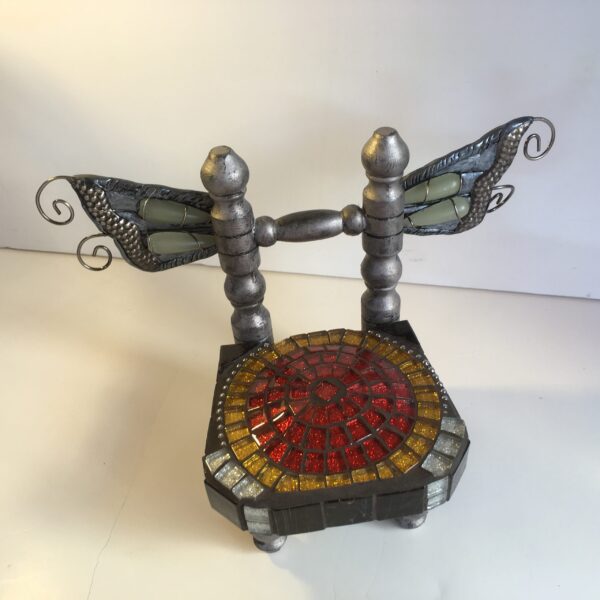 Front view of a small chair sculpture with silver butterfly wings and a red glitter mosaic seat.