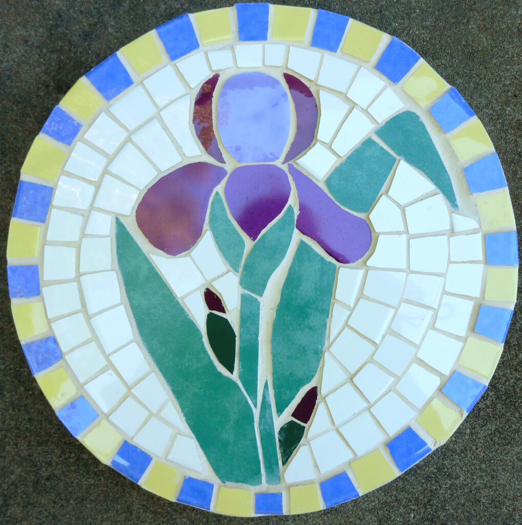 Image of a round ceramic mosaic featuring a purple iris.