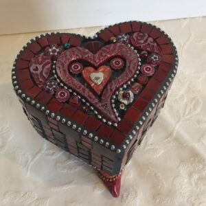 A heart-shaped box with Genie boot feet and decorated with polymer clay, glass mosaic and found objects.