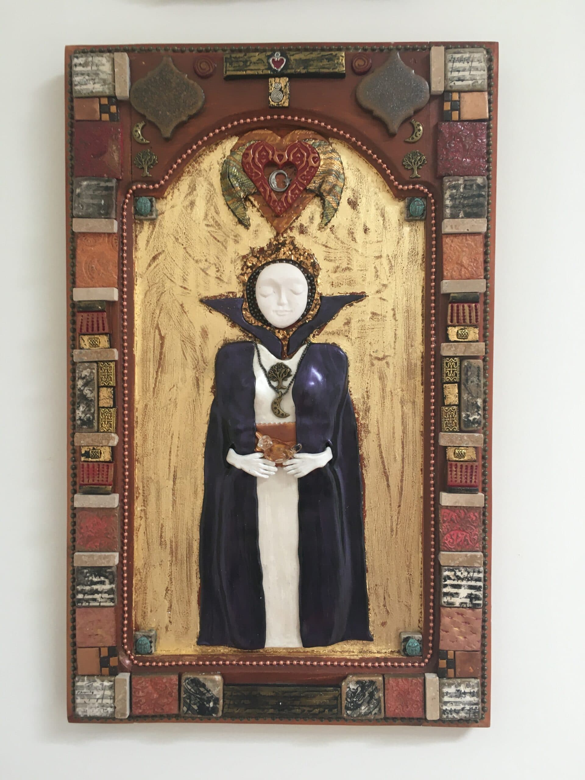 Image of a Priestess figure made of polymer clay in bas relief on wood, with a gold leaf background and mixed media frame.